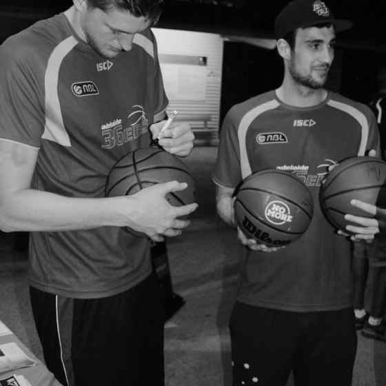 Adelaide 36ers autographing NO MORE basketballs to give to 'at risk' youth players.